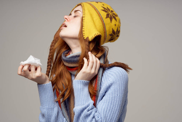 黄色い帽子の女性と暖かいセーターで鼻水の健康上の問題ナプキンを手に赤い鼻 - 写真・画像