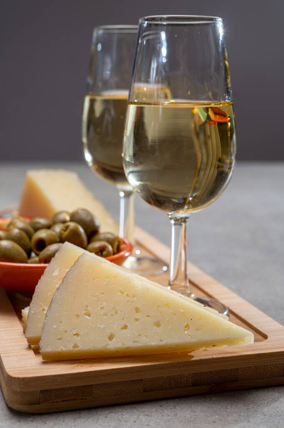 スペインのタパス、マンチェゴチーズ、グリーンオリーブ、チーズクラッカーを添えたドライコールドフィノ・シェリーワインのグラス - 写真・画像