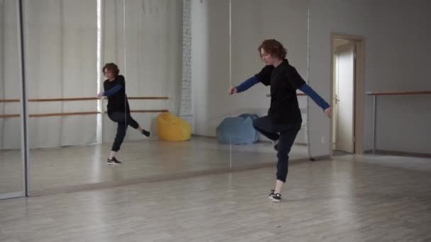 Dívka s kudrnatými vlasy diriguje online kurz moderního tance na své vlastní taneční škole s velkým zrcadlem. - Záběry, video