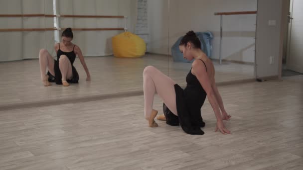 Mooi ballerina meisje toont benen strekken en splitst in de voorkant van de spiegel in de danszaal - Video