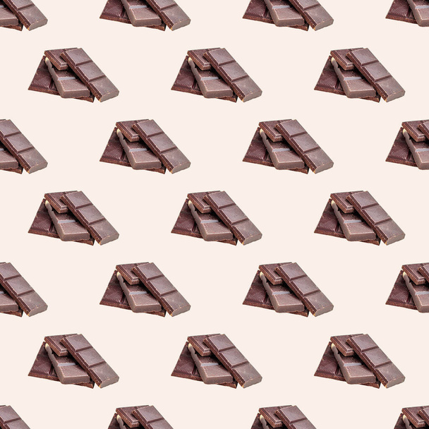 Dulces trozos de chocolate negro repiten patrón sin costuras sobre fondo claro. - Foto, Imagen