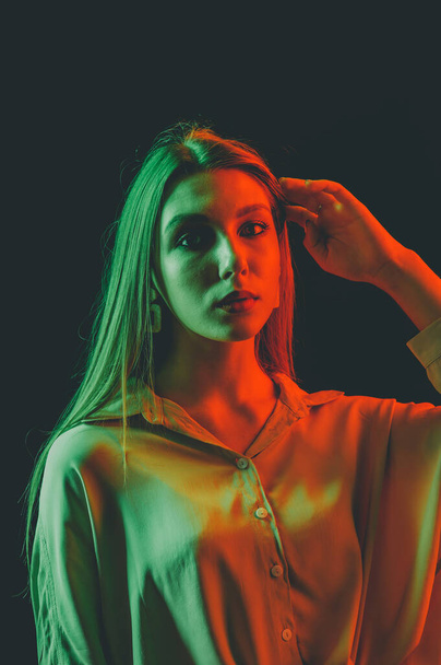 Creative portrait of a beautiful female model close-up. orange and green lighting in the Studio. - Фото, изображение
