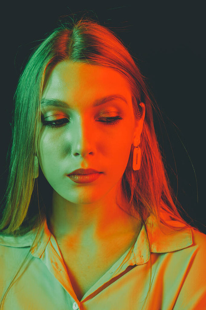 Retrato creativo de una hermosa modelo femenina de cerca. iluminación naranja y verde en el estudio. - Foto, imagen