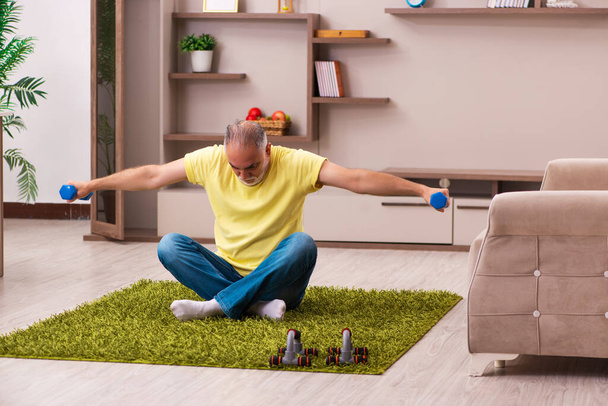 Aged man doing sport exercises at home - Photo, Image