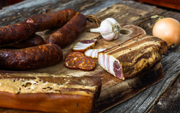 Bacon caseiro e salsicha na tábua de corte com cebola e alho - Foto, Imagem