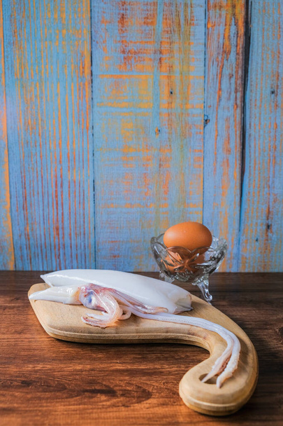 Inktvis en ei op houten ondergrond - Foto, afbeelding