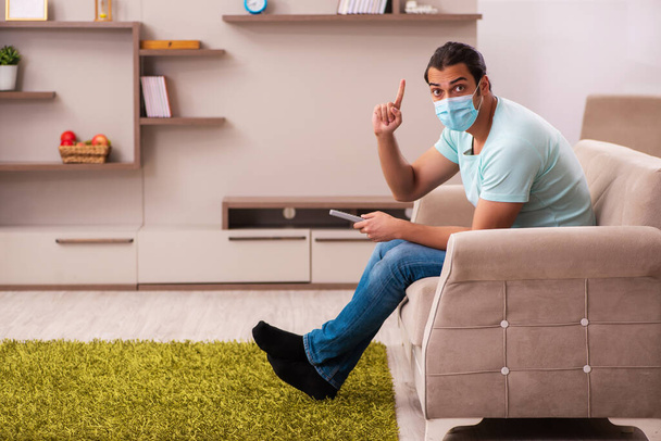 Jeune homme regardant la télévision à la maison pendant la pandémie - Photo, image