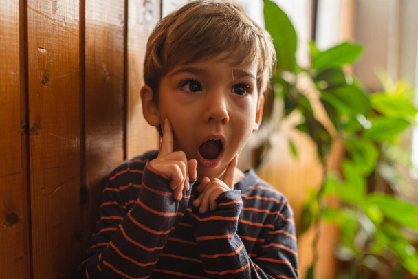 Retrato de pequeno menino caucasiano surpreso surpreso em casa vista frontal - Foto, Imagem