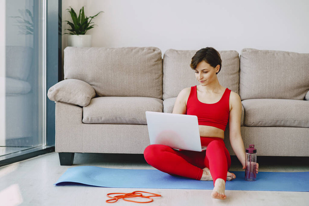 Chica en un uniforme deportivo rojo hacer yoga en casa
 - Foto, imagen