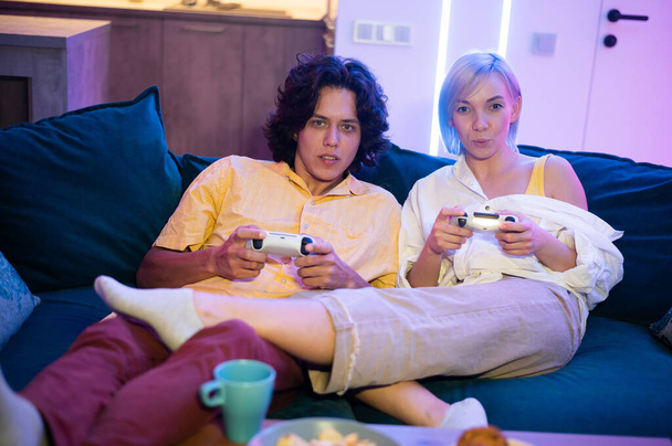 Beau jeune homme enseignant comment jouer aux jeux vidéo à sa petite amie, sur le canapé, concept de divertissement à la maison, jeux vidéo. - Photo, image