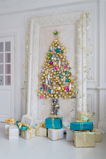 Noel için dekore edilmiş güzel bir oturma odası. Toplardan ve oyuncaklardan yapılmış bir ağacı olan büyük ayna çerçevesi. - Fotoğraf, Görsel