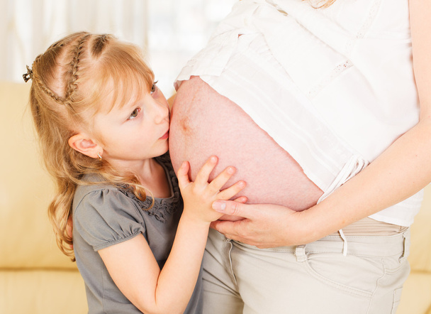 Girl kissing her mother's pregnant belly. - Valokuva, kuva