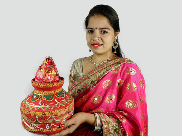 Madalyalı toprak tenceresi ve hindistan cevizi geleneksel kıyafetli bir kadının üzerinde. - Fotoğraf, Görsel
