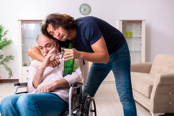 Alter Mann im Rollstuhl und junger schlechter Pfleger drinnen - Foto, Bild