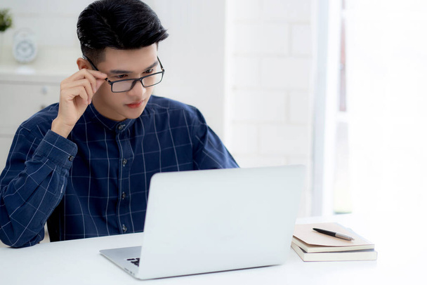 Young business man in glasses working from home with laptop computer on desk, freelance male sitting stay home using notebook for communication on table, entrepreneur in startup business, new normal. - 写真・画像