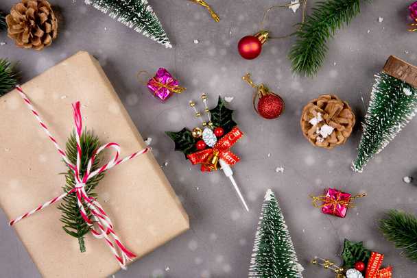 Christmas holiday composition with gift box and snow decoration, new year and xmas or anniversary with presents on cement floor background in season, top view or flat lay, copy space. - 写真・画像