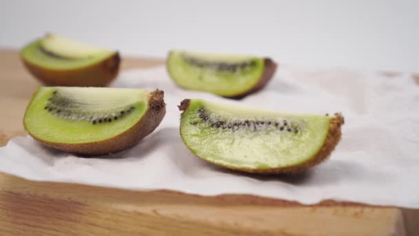 Pieces of kiwi on a cutting wooden board and a white napkin. Closeup. Selective focus - Footage, Video