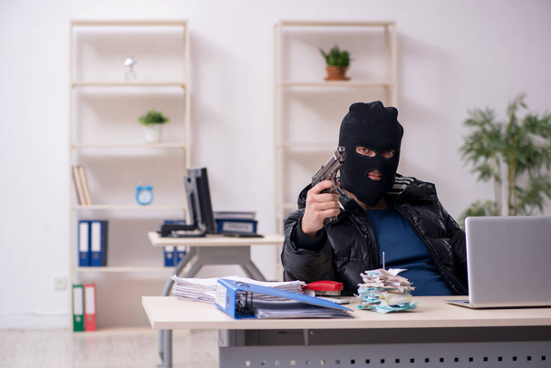 Молодий чоловік грабіжник в офісі
 - Фото, зображення