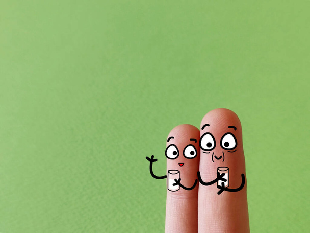 Dois dedos são decorados como duas pessoas. Eles estão bebendo leite feliz. - Foto, Imagem