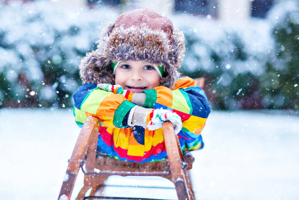 Niño disfrutando del paseo en trineo durante las nevadas. Feliz niño preescolar montando en trineo vintage. - Foto, imagen