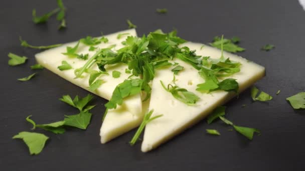 Closeup de fatias de queijo duro com salsa picada. Em uma superfície de pedra preta. Dolly Shot - Filmagem, Vídeo