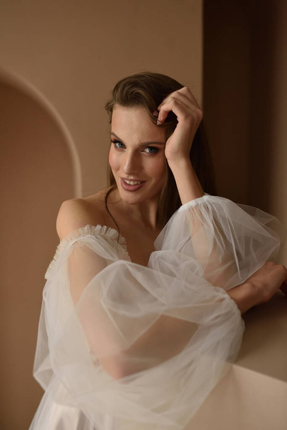 Portrait of a young beautiful bride in full growth. Girl posing in a room near the window. - Foto, Imagen