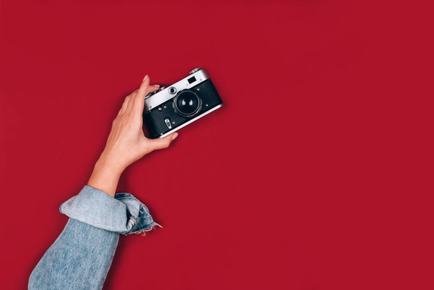 Kırmızı zemin üzerinde eski bir retro fotoğraf makinesini tutan kadın metin için fotokopi uzayı kullanıyor. Moda vintage fotoğrafçılık, çevrimiçi fotoğrafçılık okulu konsepti, seçici odak - Fotoğraf, Görsel