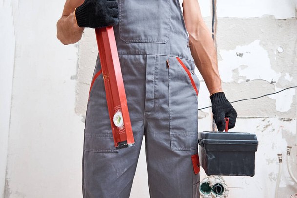 Builder man in uniform with a construction tools. Repair concept - Фото, изображение