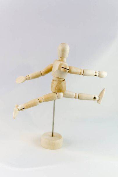 An articulated mannequin in a runner's pose in from of a white background - Fotoğraf, Görsel