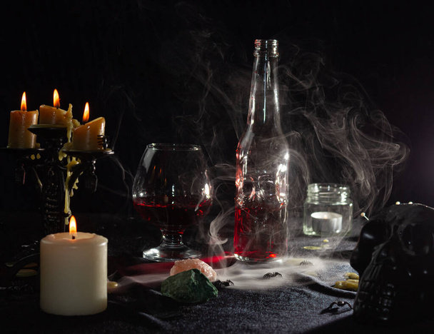 Egy üveg vörös folyadék, mint a vér és egy pohár. Varázsital. A varázslók, a boszorkányság és a mágia fogalma. Halloweeni. - Fotó, kép