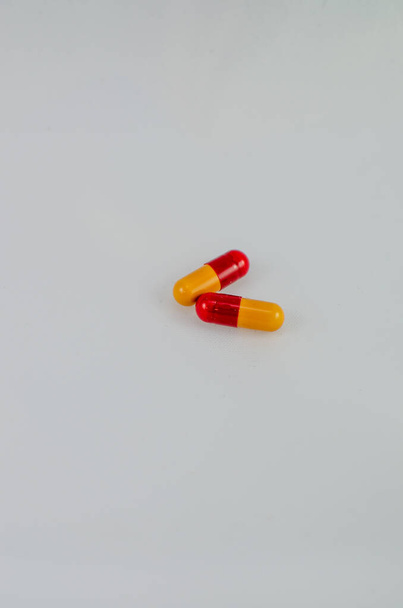 zbliżenie dwóch czerwonych i żółtych tabletek przed białym tle - Zdjęcie, obraz