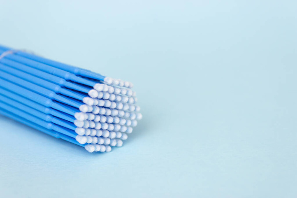 Microspazzole blu, piccoli pennelli per la pulizia di ciglia e denti. Sfondo blu. Odontoiatria, estensioni ciglia. - Foto, immagini