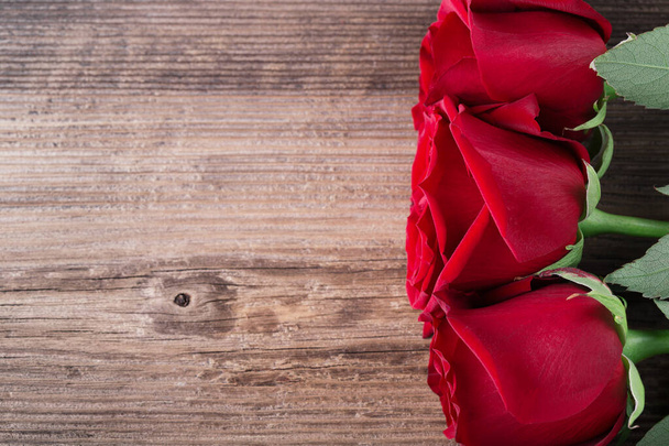 Trzy czerwone róże na drewnianym tle z copyspace miłość romans ślub koncepcja, widok z góry - Zdjęcie, obraz