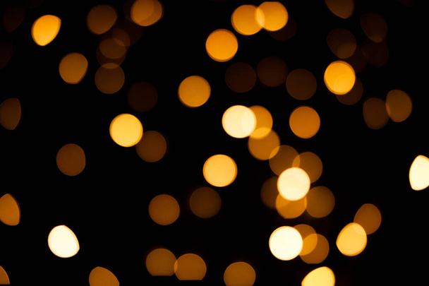 Bright yellow blurry lights on a black background. Bokeh for post-processing photos, design. - Foto, afbeelding