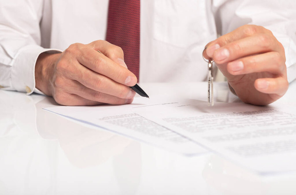 Businessman signing contract with keys in hand. real estate agreement concept. - Foto, Bild