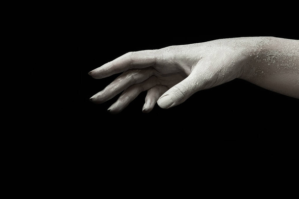 A beautiful female hand with dry skin stretches your product on a black isolated background, concept art - Valokuva, kuva