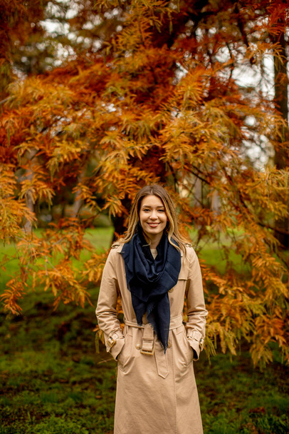 Gyönyörű fiatal nő áll az őszi parkban - Fotó, kép