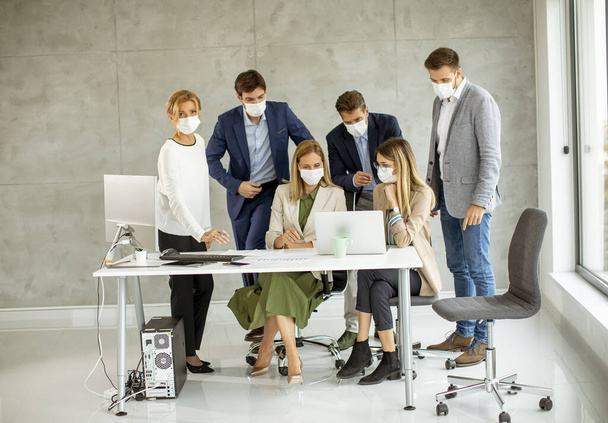 Groep van zakenmensen hebben een vergadering en werken in het kantoor en dragen maskers als bescherming tegen coronavirus - Foto, afbeelding