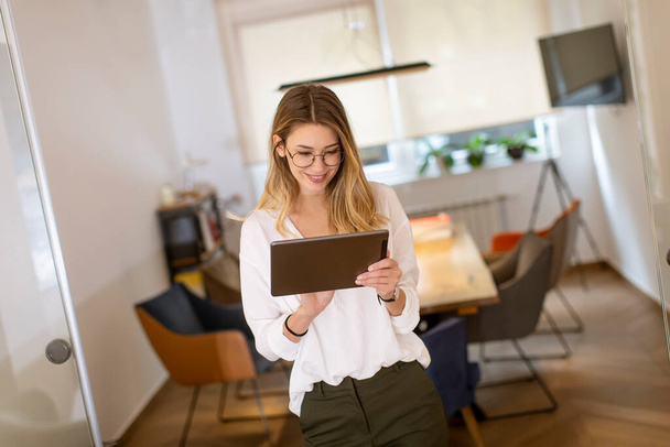 Hübsche junge Frau arbeitet mit digitalem Tablet im Büro - Foto, Bild
