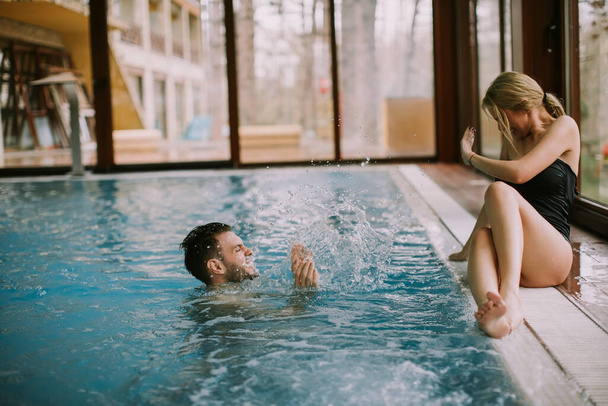 Preciosa pareja joven relajándose en la piscina de la piscina interior - Foto, Imagen
