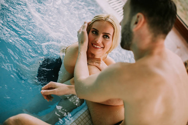 Schönes junges Paar entspannt sich am Pool des Innenpools - Foto, Bild