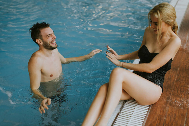 Lovely young couple relaxing on the poolside of interior swimming pool - Foto, immagini