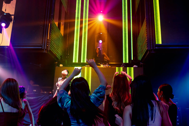 Gruppe tanzt in Disco-Nachtclub zum Beat der Musik von DJ auf der Bühne - Foto, Bild