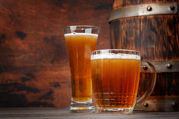 Mug and glass of light lager beer and old wooden barrel. With copy space - Photo, Image