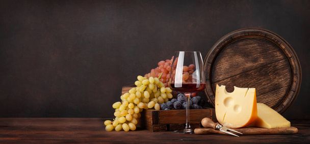Grapes, cheese, glass of red wine and old wooden barrel. With copy space - Fotoğraf, Görsel