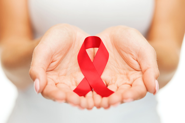 Hands holding red AIDS awareness ribbon - 写真・画像