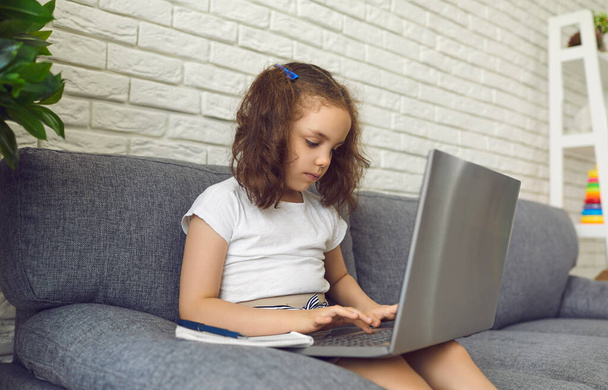 Online child education. Little girl makes video chat lesson laptop at home. - Fotó, kép