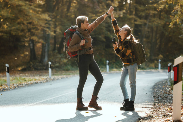 Shot of a teen girl and her mom having fun and dancing during walk together through the forest in autumn. - Photo, Image