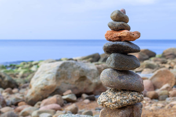 Rest and seaside vacation. Stones pyramid on the seashore at sunny day. Pebble beach, beautiful view. Concept of balanced life, harmony and relax. - Photo, Image