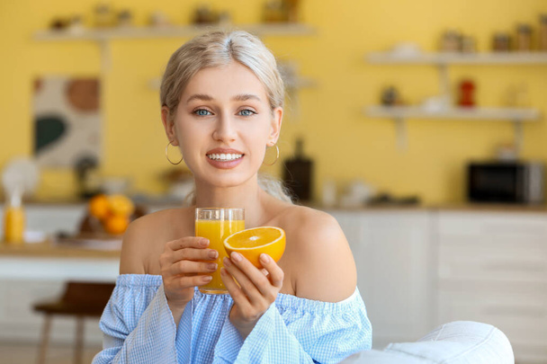 Gyönyörű fiatal nő narancslevet iszik otthon. - Fotó, kép